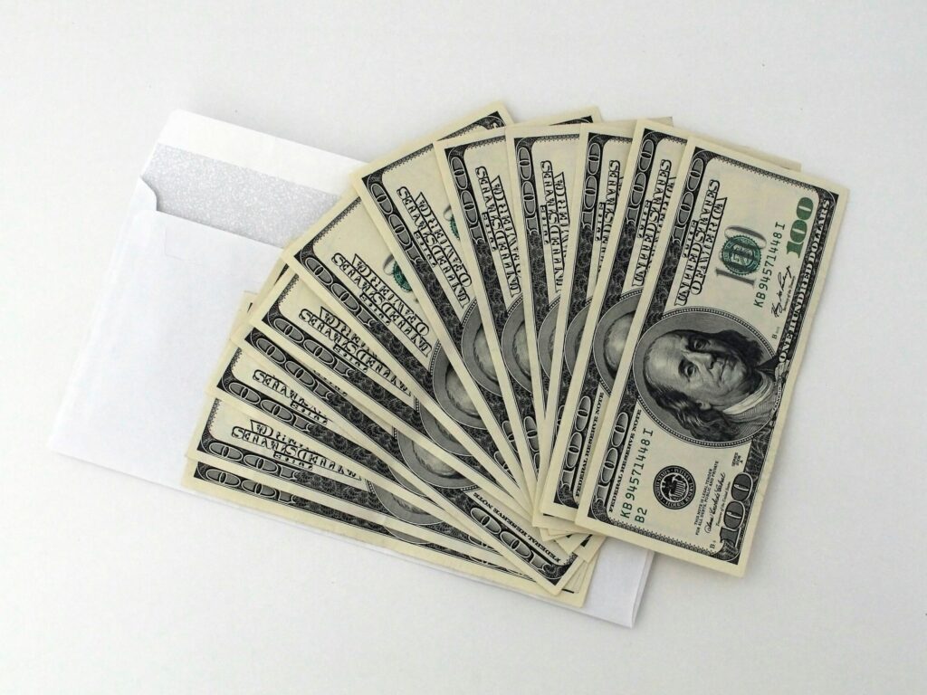 Stack of hundred-dollar bills placed over an envelope, symbolizing fast funding from a quick business loan online.
