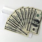 Stack of hundred-dollar bills placed over an envelope, symbolizing fast funding from a quick business loan online.